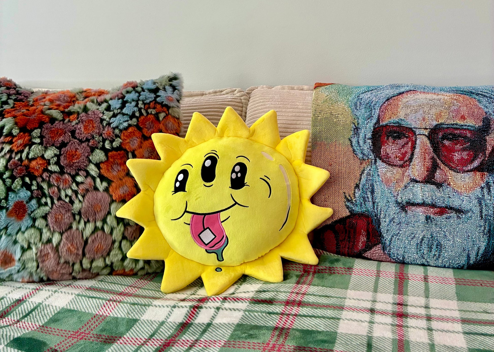 Sun-shaped pillow with a face on a couch with other pillows