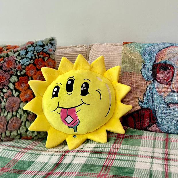Sun-shaped pillow with a face on a couch with other pillows